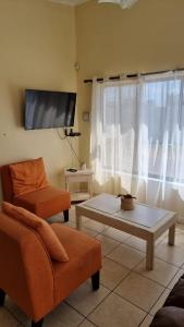 sala de estar con sofá, mesa y TV en Cabañas Pinamar en La Serena