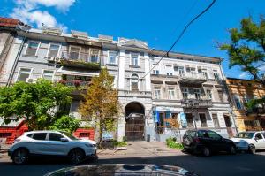 a large white building with cars parked in front of it at Suites on Chaikovskogo in Odesa