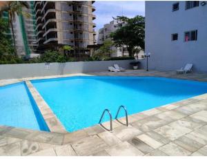 a large blue swimming pool next to a building at Condomínio Itaparica III in Guarujá