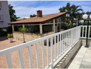 a white fence next to a building with trees at Condomínio Itaparica III in Guarujá