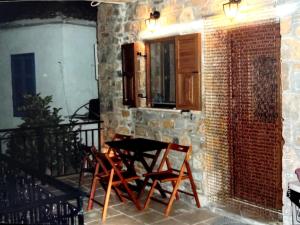 een patio met een tafel en stoelen aan een bakstenen muur bij traditional house in Androni in Mirina