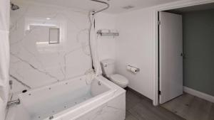 La salle de bains blanche est pourvue d'une baignoire blanche et de toilettes. dans l'établissement Clarion Pointe El Cajon San Diego East, à El Cajon