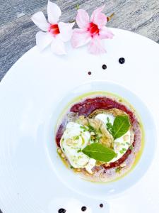 ein weißer Teller mit einem Dessert auf einem Tisch mit Blumen in der Unterkunft Auberge Des Pins in Tourrettes