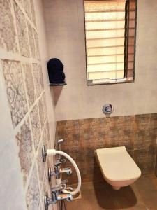 a bathroom with a toilet and a window at Swarg 5Bhk Villa Alibaug in Alibaug