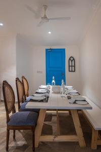 a dining room with a table with chairs and a blue door at SaffronStays Kairos Zeus, Karjat - Greek style pool villa near Camp Max in Karjat