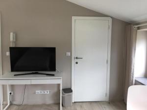 a living room with a television and a white door at Le Jardin du Thé Bord de la Meuse in Namur