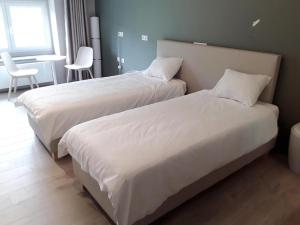 2 camas con sábanas blancas en una habitación en Le Jardin du Thé Bord de la Meuse, en Namur