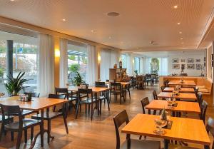 a restaurant with wooden tables and chairs and windows at Hotel Hecht in Rheineck