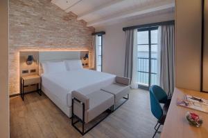 una camera con un letto bianco e un muro di mattoni di NH Collection Murano Villa a Murano