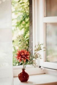 un jarrón rojo con flores sentado en el alféizar de la ventana en Landhaus Halferschenke en Dieblich