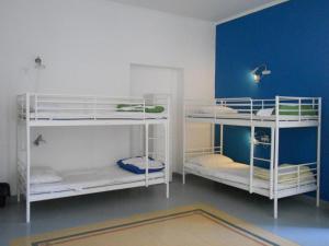 two white bunk beds in a room with a blue wall at La Controra Hostel Naples in Naples