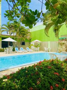 una piscina con sillas y sombrillas junto a un edificio en Pousada o Caribe de Maragogi, en Maragogi