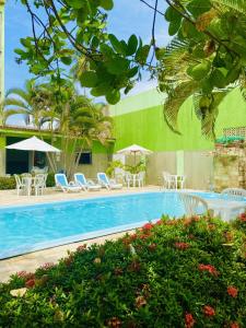 a pool with chairs and umbrellas next to a building at Pousada o Caribe de Maragogi in Maragogi