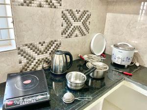 a kitchen counter top with pots and pans on it at TrueLife Homestays - Alamelu Avenue - Fully Furnished AC 2BHK Apartments in Tirupati - Walkable to Restaurants & Super Market - Fast WiFi - Kitchen - Easy access to Airport, Railway Station, Sri Padmavathi & Tirumala Temple in Tirupati