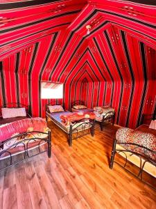 a room with three beds in a red tent at Wadi Rum White Mountain Camp in Wadi Rum