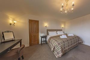 1 dormitorio con cama, mesa y lámpara de araña en 3 Bedroom Barn Conversion -Garden View - Ty Cerrig Barn en Corwen