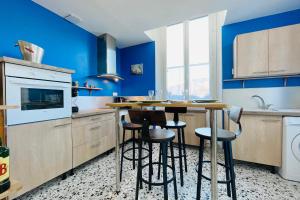 a kitchen with blue walls and a table and stools at The City in the Country #CB in Gières