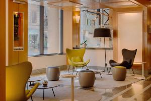 a lobby with chairs and tables and a window at NH Milano Machiavelli in Milan