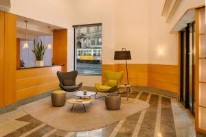 a lobby with chairs and tables and a window at NH Milano Machiavelli in Milan