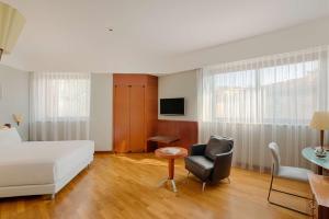ミラノにあるNH ミラノ マキャベリのベッド、椅子、テーブルが備わるホテルルームです。