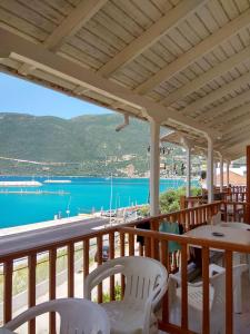a balcony with white chairs and a view of the water at Kostas Studios II in Vasiliki