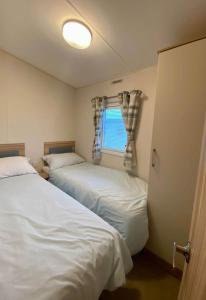 two beds in a small room with a window at The Hudson @ Silversands in Lossiemouth