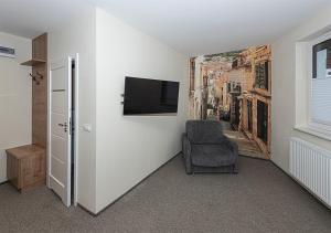 a room with a chair and a tv on a wall at Apartamenty Piano in Świeradów-Zdrój