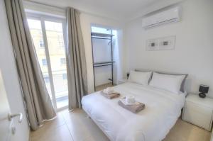 a bedroom with a white bed and a window at Spacious and tastefully furnished 2 bedroom apartment DDIF1-3 in Il-Gżira