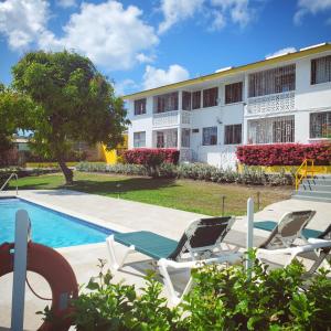 a resort with a swimming pool and chairs and a building at Adulo Apartments in Bridgetown