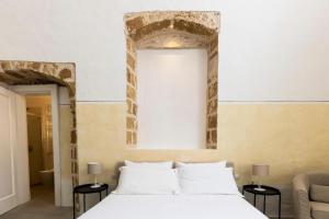 a bedroom with a large white bed with two tables at Palazzo Balsamo in Gallipoli