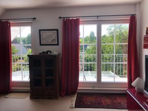 a living room with two large windows with red curtains at Charmante 2-Zimmer Wohnung in Hoisdorf