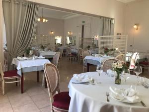 a restaurant with white tables and chairs and a mirror at Logis - Hostellerie Le Chatel Nangis in Nangis