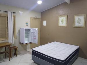- une chambre à l'hôpital avec un lit et un réfrigérateur dans l'établissement Canto Sul Suítes, à Ubatuba