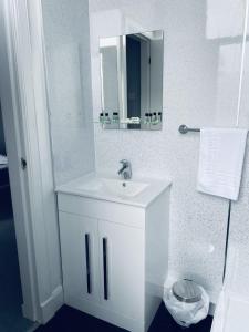 a white bathroom with a sink and a mirror at The Portmann Hotel in Kilmarnock