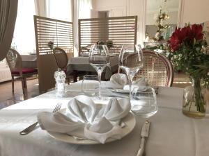 una mesa con un plato blanco y copas de vino. en Logis - Hostellerie Le Chatel Nangis, en Nangis