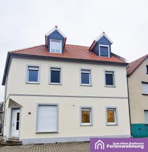 a white house with a red roof at Ferienwohnung Zum Alten Radlereck in Lauchhammer