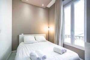 um quarto com uma cama com lençóis brancos e uma janela em Frontière Monaco, appartement moderne rénové - AH em Beausoleil