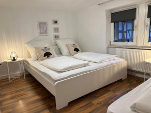 a white bed in a room with wooden floors at MODERNES HAUS FÜR 7 GÄSTE 90m2 TV NETFLIX WLAN in Momlingen