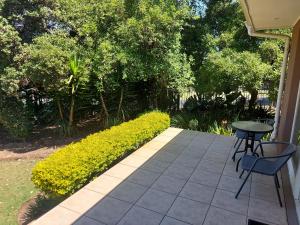 Mimosa Self-Catering Studio Durbanville في دوربانفيل: فناء به طاولة وكراسي وشجيرات