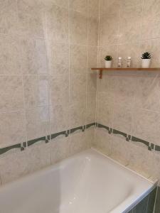 a white bath tub in a tiled bathroom at Gyöngy Apartman in Sopron +2 photos