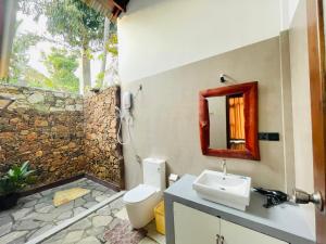 a bathroom with a sink and a toilet and a mirror at Mango Tree House in Udawalawe