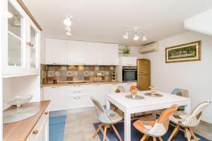a kitchen with white cabinets and a white table and chairs at Holiday Home Tezoro Royal in Dubrovnik