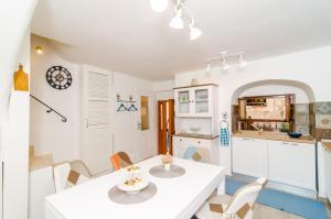 a kitchen and dining room with a white table and chairs at Holiday Home Tezoro Royal in Dubrovnik