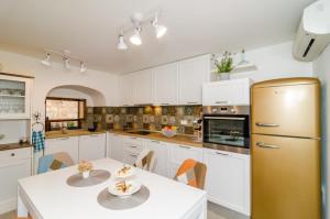 a kitchen with white cabinets and a table and a refrigerator at Holiday Home Tezoro Royal in Dubrovnik