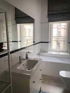 a white bathroom with a sink and two windows at Rabarbar in Łódź