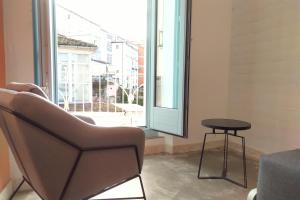 una silla y una mesa en una habitación con ventana en Apartamentos Turísticos As Burgas 6 by Bossh Hotels, en Ourense