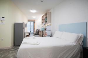 a bedroom with a white bed and a refrigerator at Apartamentos Turísticos As Burgas 6 by Bossh Hotels in Ourense