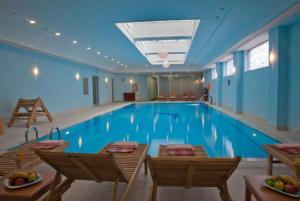 a large swimming pool in a hotel with tables and chairs at Eliz Hotel Convention Center Thermal Spa & Wellnes in Ankara