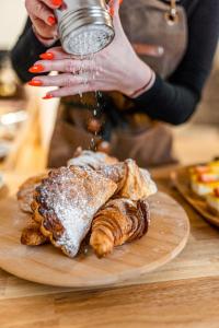 a woman pouring powdered sugar over a plate of pastries at JEZ&SPI Sušice in Sušice