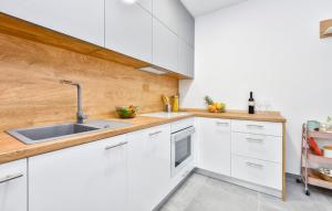 una cocina con armarios blancos y fregadero en Kalimero apartman A1 en Križevci